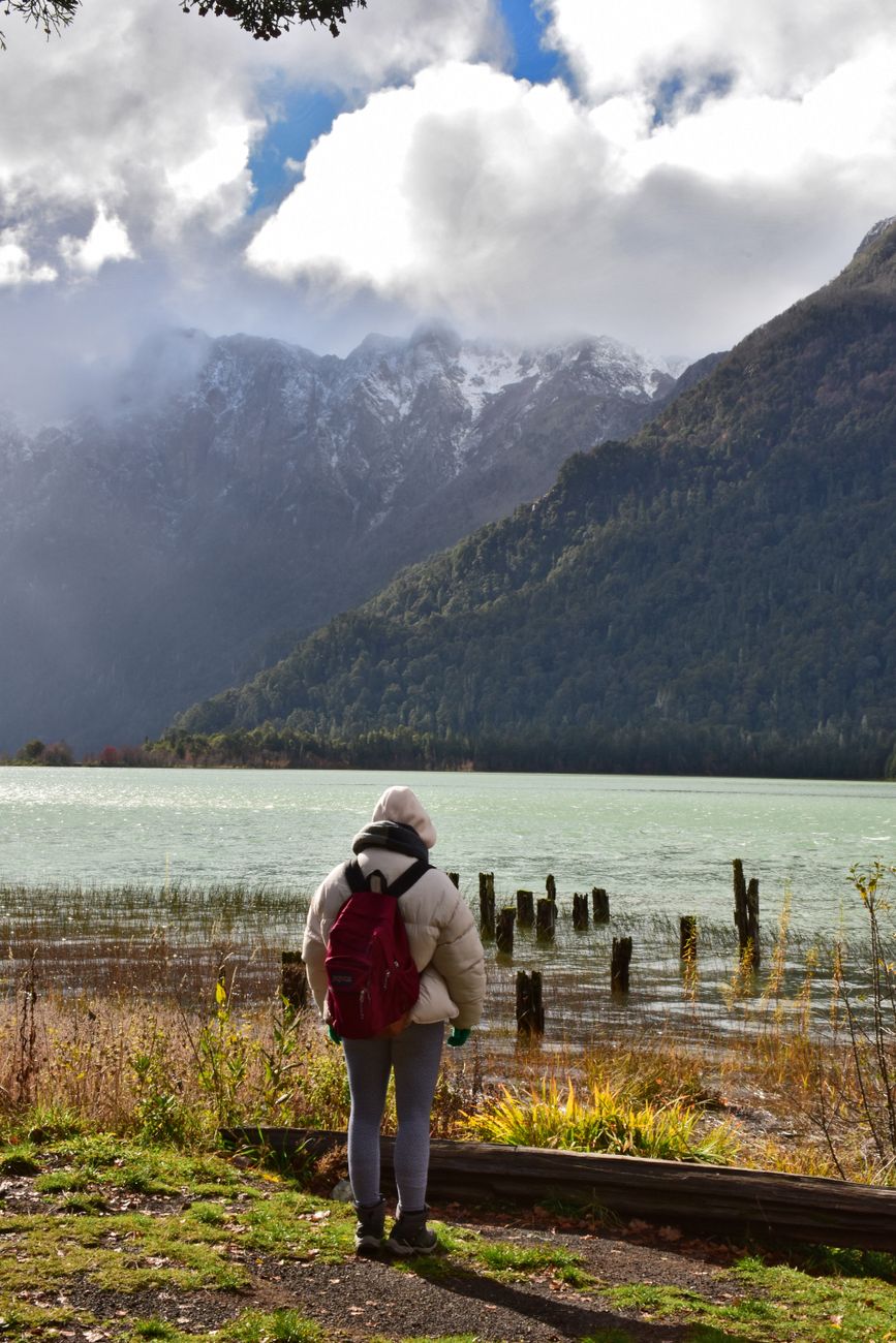 Traveler looking out at peaceful mountain lake